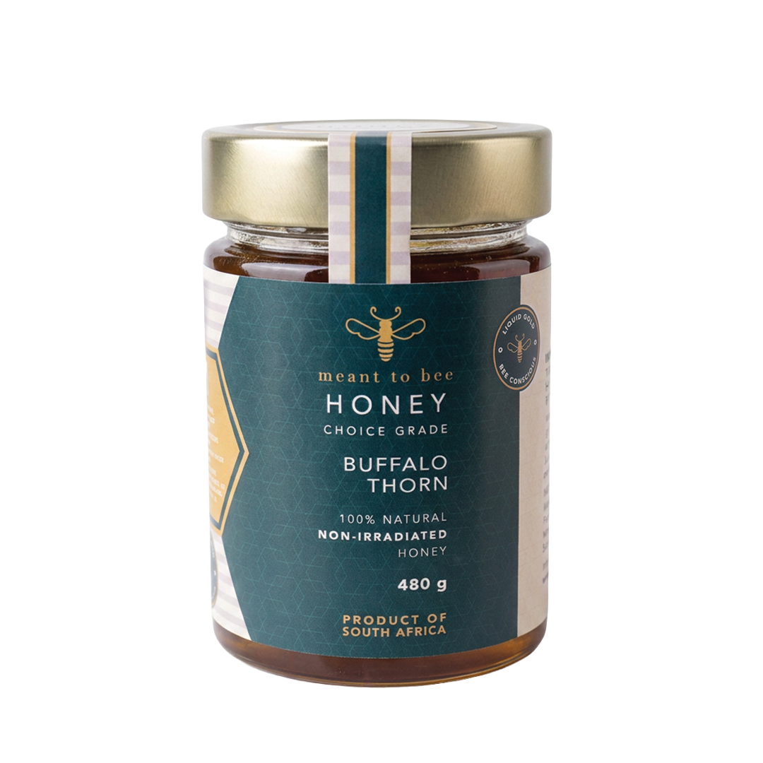 A glass jar of Meant To Bee Buffalo Thorn honey with a gold lid and deep green label.
