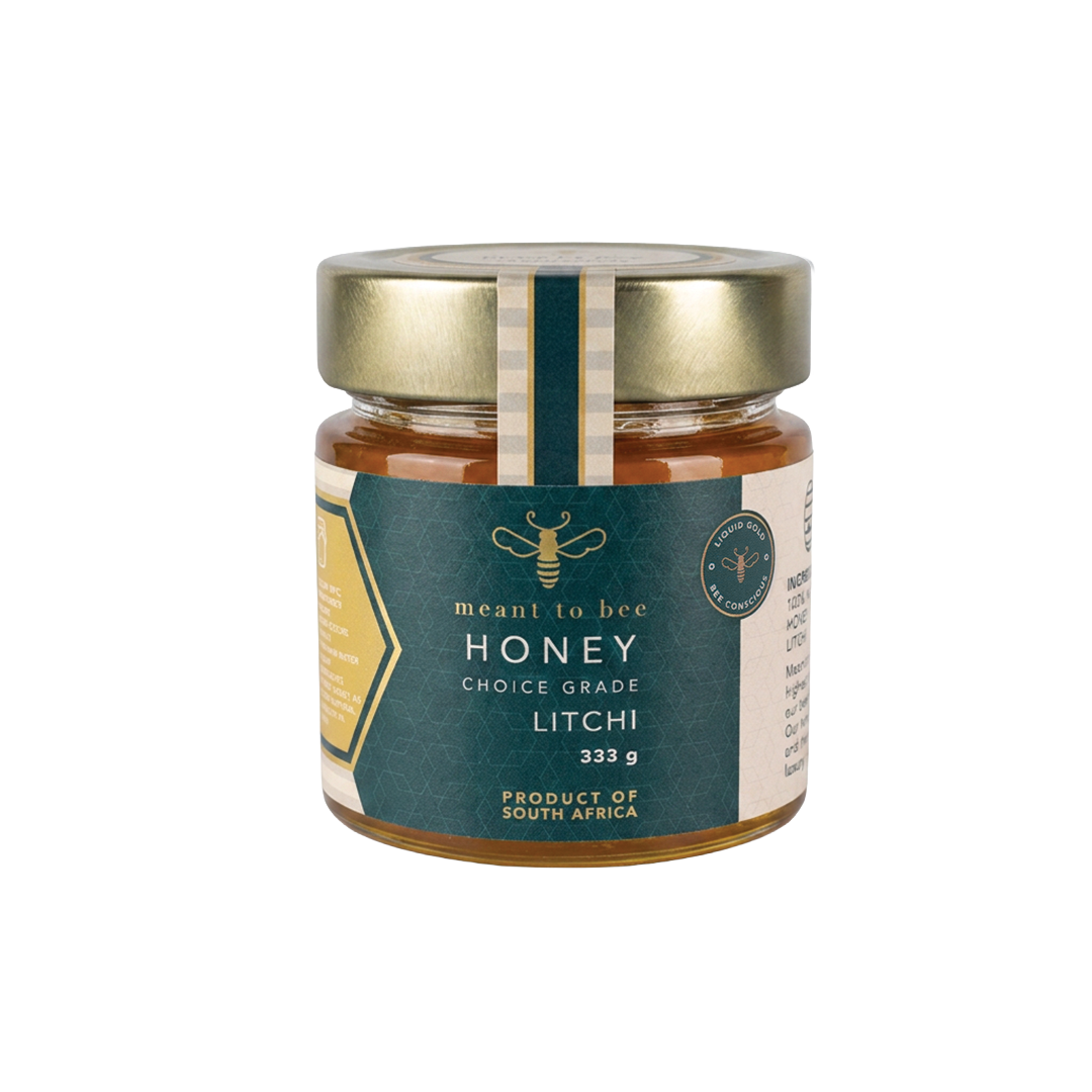 A glass jar of Meant To Bee Litchi honey with a gold lid and deep green label.